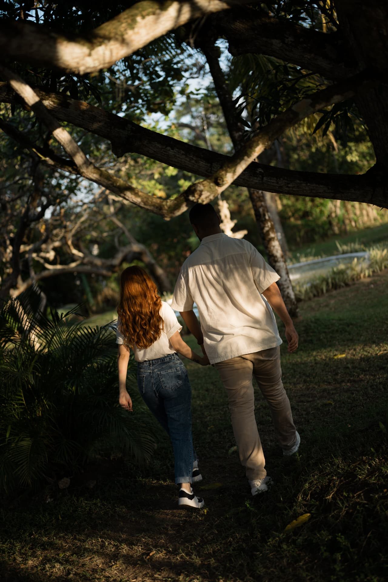 Casal de mãos dadas caminhando sob as árvores do jardim da Chácara